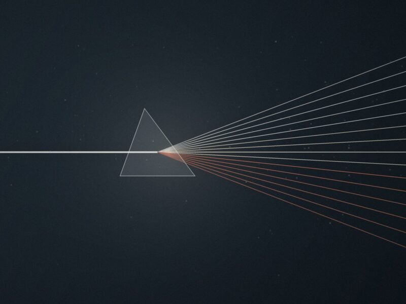 A single beam of light entering a glass prism and leaving as a fan of cream and terracotta rays