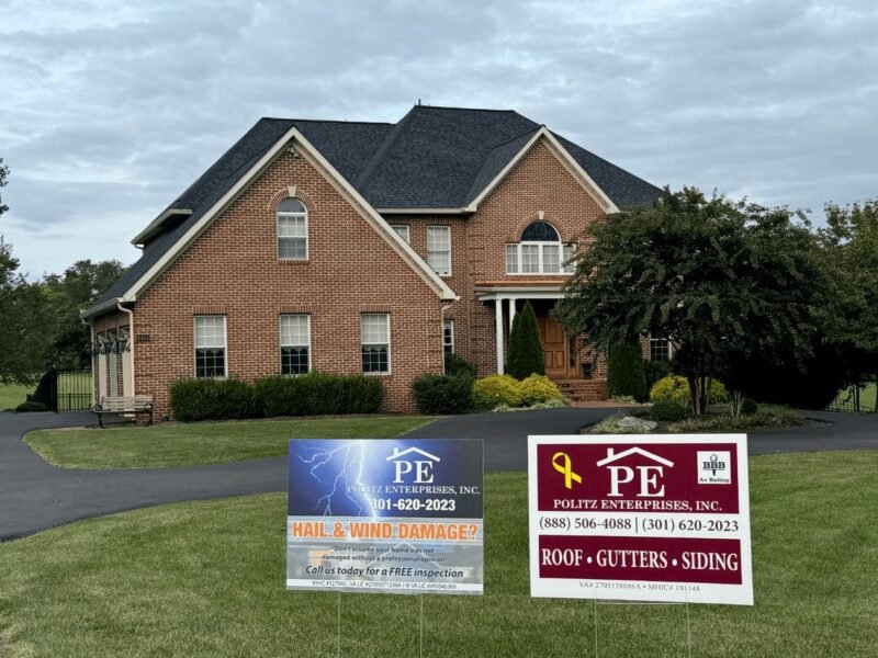 Brick house with Politz Enterprises roofing yard signs on the lawn